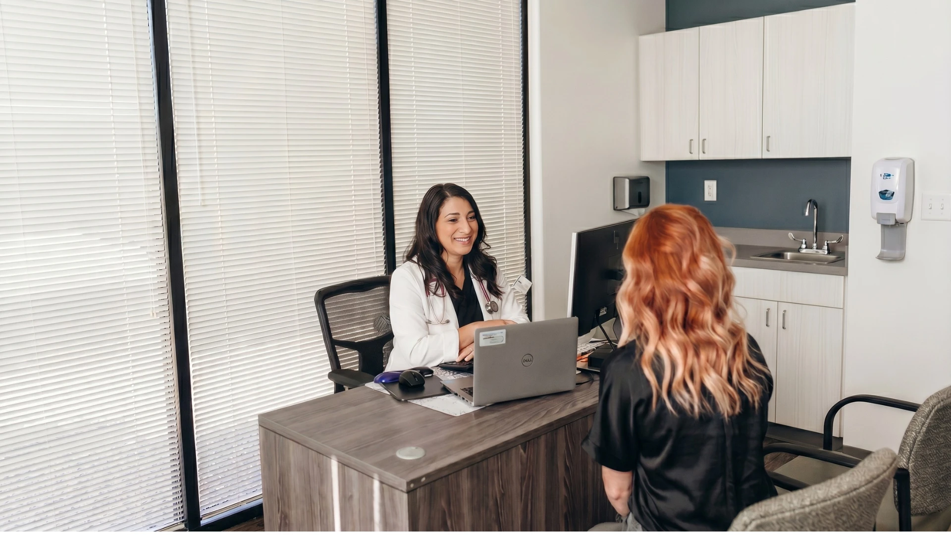 Family Nurse Practitioner Lauren Bedrock consulting with a patient in a modern Henderson medical office.